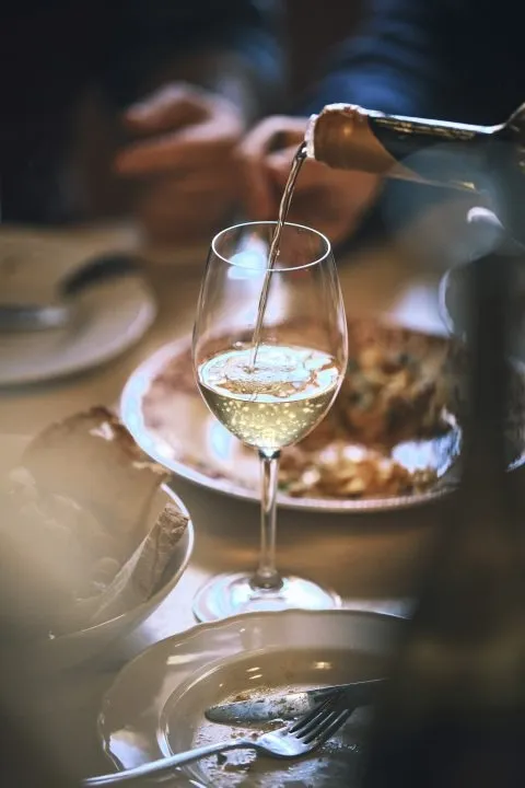 Copo de vinho branco a ser servido à mesa com pratos tradicionais
